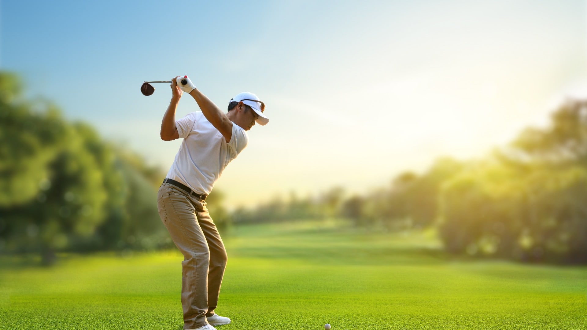 Asian man golfer driver swing before hitting golf ball down the fairway.