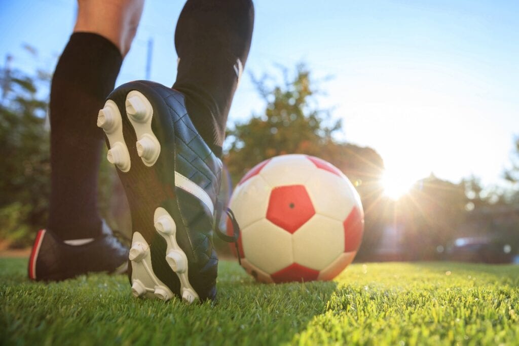 Woman feet and a soccer ball on the grass, closeup. Female football